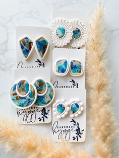 three different pieces of jewelry sitting on top of a card next to some dried grass