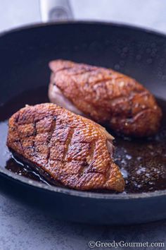 two pieces of meat cooking in a skillet