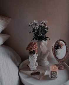 a white table topped with a mirror and vases filled with flowers next to a candle