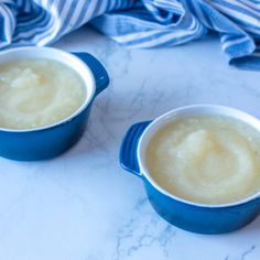 two small blue bowls filled with food on top of a table next to a towel