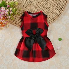 a red and black plaid dress sitting on top of a table next to a straw hat