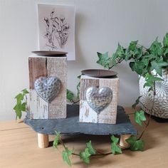 two wooden blocks with hearts on them sitting on a table next to potted plants