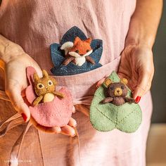 the woman is holding three felt animals in her hands