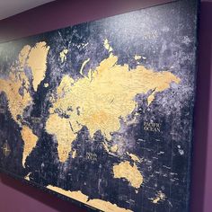 an old world map is hanging on the wall in a room with purple walls and wood flooring