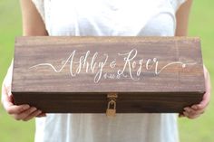 a person holding a wooden box with writing on it