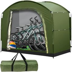 a green tent with two bikes in it and a ball on the ground next to it