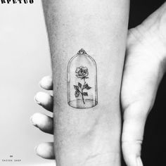 a rose in a glass bottle tattoo on the left inner forearm and arm, it is black and white