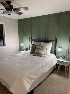 a bedroom with green paneled walls and white bedspread, two lamps on either side of the bed