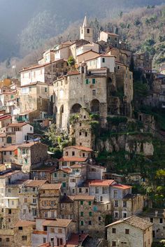 an old village on the side of a mountain with lots of buildings and trees around it