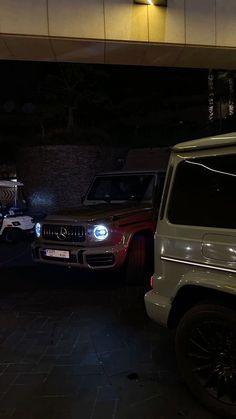 two jeeps parked next to each other in a parking lot at night with lights on