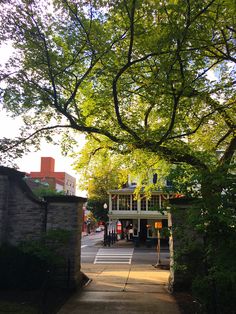 an entrance to a park with trees and buildings in the background