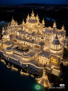 an elaborate building lit up at night with lights on the top and bottom floors, surrounded by water