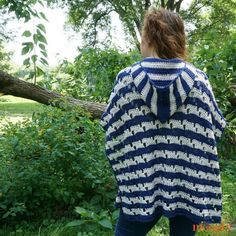 a woman standing in front of a tree wearing a blue and white striped sweater