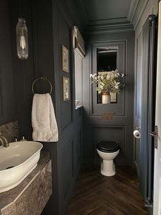 a white toilet sitting in a bathroom next to a sink and wooden floored walls