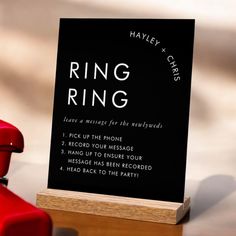 a black sign sitting on top of a wooden table next to a red toy car