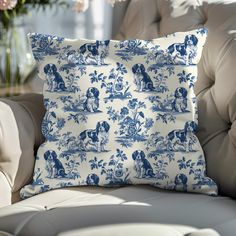 a blue and white pillow sitting on top of a couch next to a vase with flowers