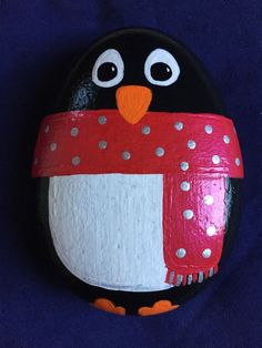 a painted rock with a penguin wearing a scarf