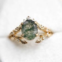 This exquisite Moss Agate ring set features the serene beauty of nature captured in elegant simplicity. Crafted with care, it showcases the captivating charm of moss agate, a stone renowned for its lush green hues and intricate patterns reminiscent of verdant forests. The delicate leaf motif adorning the band adds a touch of organic grace, enhancing the ring's natural charm. Nature-inspired Green Oval Emerald Ring, Elegant Moss Agate Rings With Natural Inclusions, Nature-inspired Oval Emerald Ring, Wedding Agate Cabochon Jewelry, Nature-inspired Emerald Ring, Elegant Emerald Rings With Natural Stones, Elegant Green Moss Agate Rings, Nature-inspired Agate Rings With Natural Inclusions, Nature-inspired Moss Agate Jewelry With Natural Inclusions