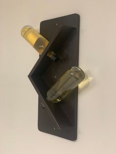 two wine bottles are placed in the shape of a bottle holder on a white wall