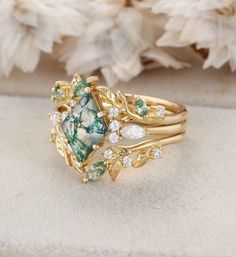 a green and white ring sitting on top of a piece of cloth next to flowers