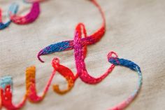 the word jesus written in multicolored thread on a piece of fabric