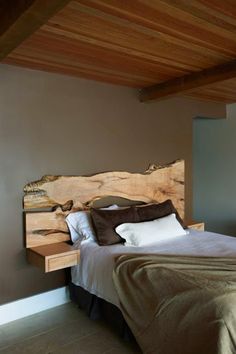 a bed sitting in a bedroom next to a wooden headboard on a wall mounted shelf