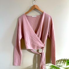 a pink sweater hanging on a wall next to a potted plant