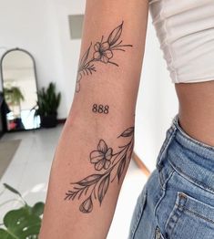 a woman's arm with flowers on it and the number 868 tattooed on it