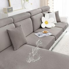 a living room with a couch and white flowers on the table in front of it