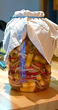 a jar filled with sliced bananas sitting on top of a wooden table next to scissors