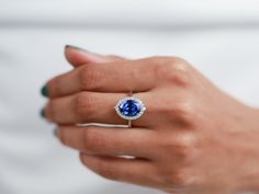 a woman's hand holding a ring with a blue stone