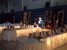 several tables covered in white tablecloths with lights on them