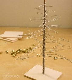 a small christmas tree made out of wire and gold balls on a table with other decorations