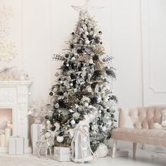 a decorated christmas tree in a living room with white and silver decorations on the walls