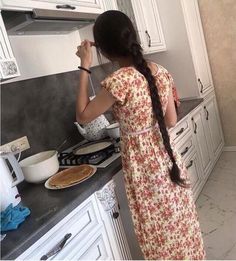 a woman standing in a kitchen next to a stove top oven