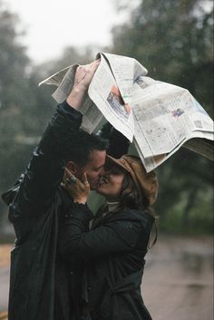 a man and woman kissing in the rain with newspapers on their heads as they stand under an umbrella