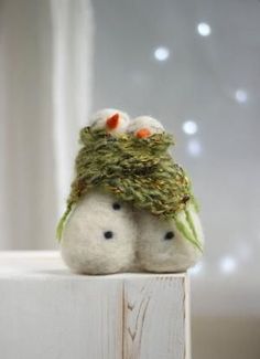 two small stuffed animals sitting on top of a wooden block with lights in the background