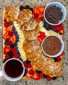 an assortment of pastries and fruit on a platter with dipping sauces for dipping