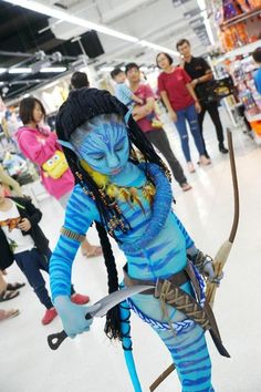 a woman dressed as avatar from avatar is holding a bow and arrow in a store