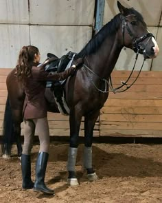 a woman in riding gear standing next to a horse