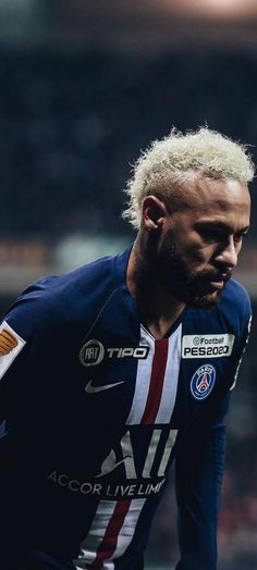 a soccer player with blonde hair and blue uniform in the middle of a field during a game