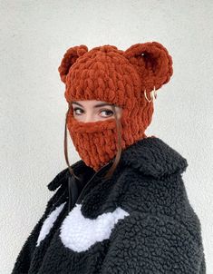 a woman wearing an orange knitted bear hat and black jacket with white letters on it