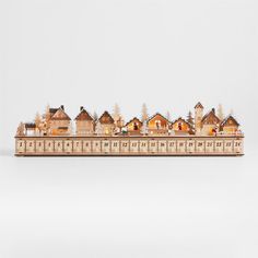 a wooden model of a city with buildings and trees on it's sides, in front of a white background