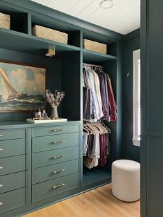 a walk in closet filled with lots of drawers and clothes on top of shelves next to a painting