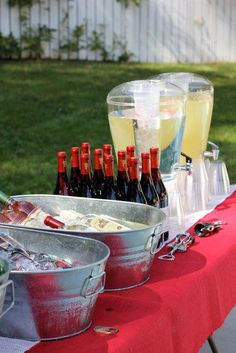 several bottles of wine are sitting on a table with ice buckets and other drinks