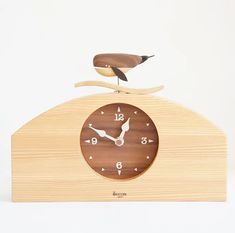 a wooden clock with a bird sitting on it's top and the time is 11 00