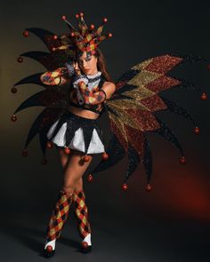 a woman dressed as a fairy with wings and beads on her body, standing in front of a dark background