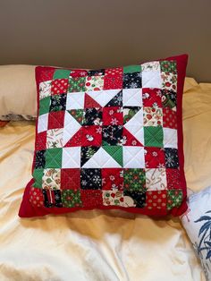 a red and green quilted pillow sitting on top of a bed