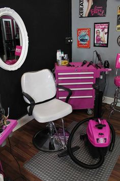 a pink and white chair in front of a black wall with pictures on the walls