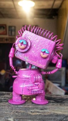 a pink toy robot sitting on top of a wooden table